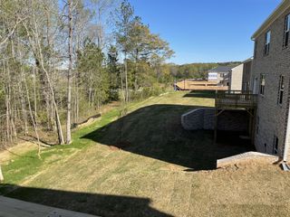 A picturesque backyard with lush greenery and wooden deck in Broder Farm by D.R. Horton (Stockbridge, GA).