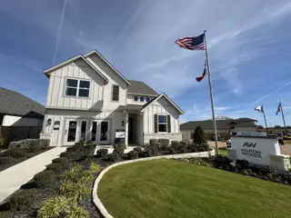 A modern white home with a landscaped yard in Patterson Ranch by Ashton Woods (Georgetown, TX).
