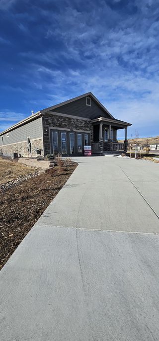 A charming stone-accented home with a spacious driveway in Rhyolite Ranch by Kauffman Homes (Castle Rock, CO).