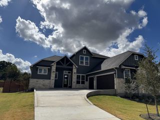 A charming home with dark siding and stone accents in Broken Oak by Chesmar Homes (Georgetown, TX).