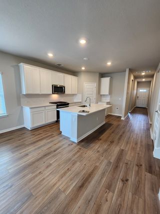 A bright open-concept kitchen with white cabinetry, stainless steel appliances, and a large island with bar seating.