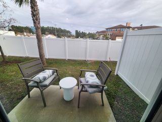 A cozy patio with two chairs and a table overlooking a fenced yard. Ideal for relaxation and enjoying the outdoors.