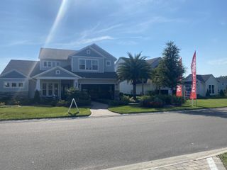 A charming blue house with manicured lawn and palm trees in Middlebourne by ICI Homes (St. Johns, FL).