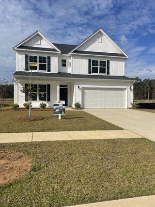 A charming white two-story home with black shutters and a neat lawn in Parker's Preserve by Eastwood Homes (Ridgeville, SC).