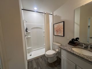 Model Home A modern bathroom featuring a sleek shower, granite-topped vanity, and elegant decor.