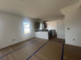 A bright, under-construction kitchen with white walls, dark cabinets, and natural light streaming through windows.