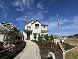 A welcoming model home with a cozy front porch and manicured garden in Casinas at Gruene by Brightland Homes (New Braunfels, TX).
