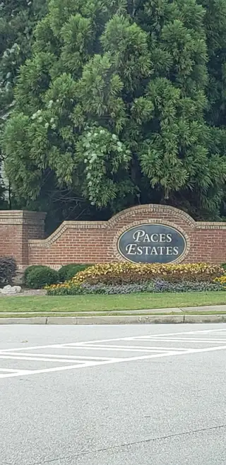 A charming entrance with brick signage and lush greenery at Paces Estates by McKinley Homes in Lithia Springs, GA.