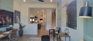 Model Home A stylish home office featuring an accent wall, modern décor, and an open view of the kitchen.