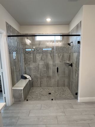 A spacious, tiled walk-in shower with a bench and elegant fixtures.