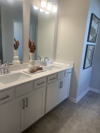 A sleek bathroom with dual sinks, chic lighting, and elegant wall art. Neutral tones create a calming, modern atmosphere.
