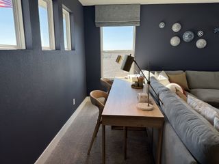 Model Home A cozy, modern study nook with a sleek desk, plush seating, and navy accent walls adorned with artistic decor plates.