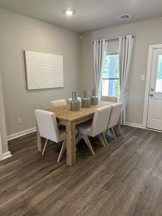 A cozy dining area with a wooden table, sleek chairs, abstract artwork, and soft natural light.