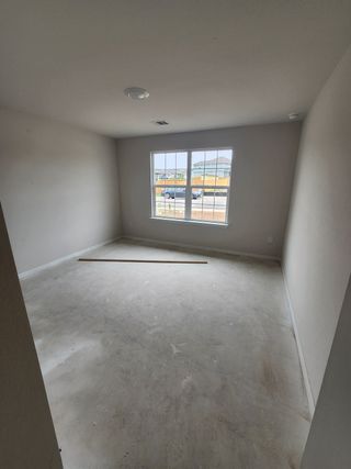 An unfinished room featuring bare concrete floors and a large window, allowing natural light to pour in.