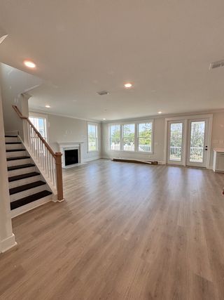 An airy living space with wood floors, a cozy fireplace, and large windows offering natural light and scenic views.