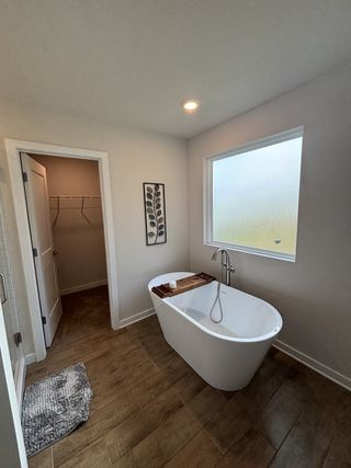 A serene bathroom with a freestanding tub, wood floor tiles, and soft lighting for a spa-like retreat.