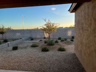 A serene backyard with desert landscaping and a view of a stone wall and sky.