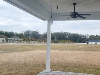 Street view A spacious backyard view with a covered patio and ceiling fan, offering scenic tranquility in Sandy Ridge by SEDA New Homes (Yulee, FL).