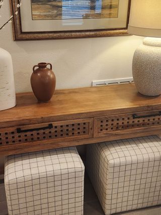 A stylish entryway console with woven details, decorative vases, and soft ottomans, creating a warm and inviting welcome.