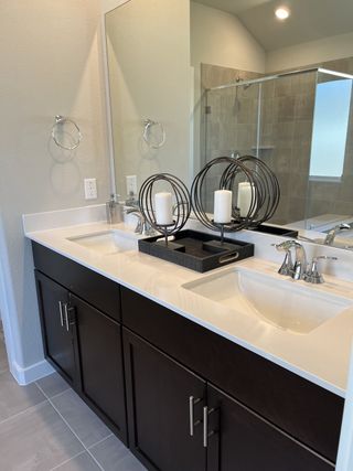 A sleek bathroom featuring a dual-sink vanity with dark cabinetry, elegant fixtures, and modern decorative accents.