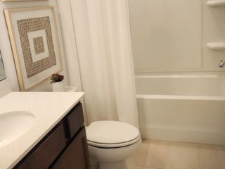 Model Home A cozy bathroom with a sleek vanity, framed art, and a pristine bathtub for a relaxing retreat.