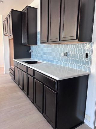 Sleek kitchen with dark cabinets, glossy backsplash, and light countertops for modern elegance.