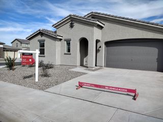 Street view A modern gray stucco home with a spacious driveway in Tirreno at IronWing by Beazer Homes (Litchfield Park, AZ).