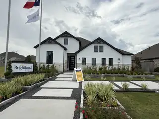 Street view A beautiful white brick home with modern design in Oakwood Estates by Brightland Homes (Waller, TX).