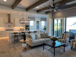A stylish open-concept living space with a chic kitchen, wood beams, sliding glass doors, and elegant lighting.