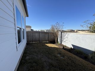 A cozy backyard with a wooden fence and bright siding in Cielo East by Masonwood Homes (Round Rock, TX).