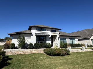 A beautiful modern home with a manicured lawn in 6 Creeks by Perry Homes (Kyle, TX).