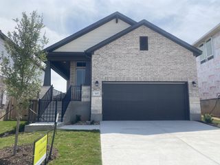 A charming brick home with a sleek black garage in Turner's Crossing by Tri Pointe Homes (Austin, TX).