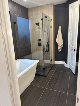 Model Home A modern bathroom featuring a sleek glass shower, freestanding tub, and elegant tiled walls.