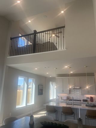 An inviting open-concept living space with a modern kitchen, airy loft, and sleek lighting fixtures.