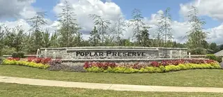 A welcoming stone entrance with lush landscaping at Poplar Preserve by D.R. Horton in Newnan, GA.