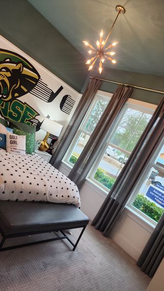 A trendy bedroom with bold sports-themed decor, a tufted bench, and large windows for an abundance of natural light.