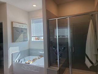 A bright bathroom with a sleek glass shower, soaking tub, and modern art piece on the wall.