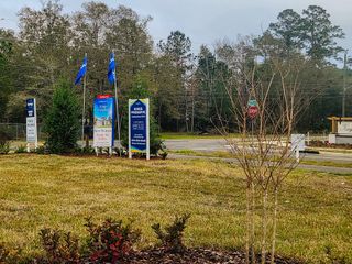 Street view New homes available in Kings Preserve by Breeze Homes, Jacksonville, FL. Signs and lush greenery enhance the inviting entrance.