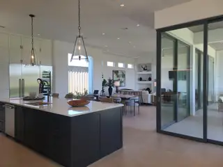 A modern open-concept kitchen with sleek cabinetry, island seating, and expansive glass doors leading to a bright living area.
