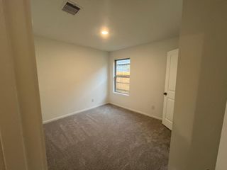 A spacious bedroom with soft carpeting and a large window, creating a peaceful and inviting retreat.