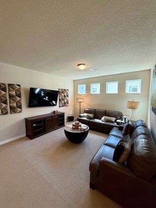 A cozy living room with leather sofas, a wall-mounted TV, modern art, and ambient lighting.