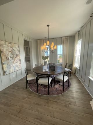 A cozy dining room with a round table, elegant chandelier, and artistic wall decor.