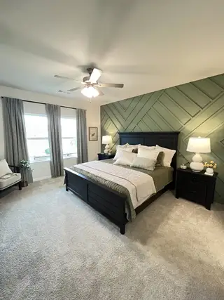 A serene bedroom with textured green accent wall, cozy beige carpet, and elegant dark wood furniture.