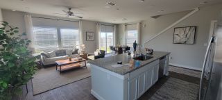 Model Home A bright, open-plan living area featuring a modern kitchen island, cozy seating, and ample natural light.