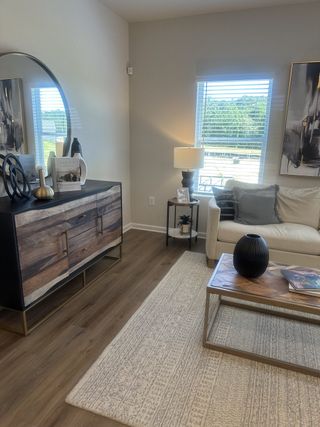 A cozy living room with modern decor, featuring a wooden sideboard, light sofa, and elegant window view.