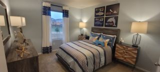 A cozy bedroom featuring nautical-themed decor, striped bedding, and modern lighting for a serene ambiance.