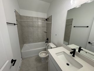A sleek bathroom featuring a tiled bathtub, white vanity, and black fixtures.