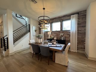 Model Home A modern dining area with a rustic brick accent wall, stylish lighting, and elegant decor.
