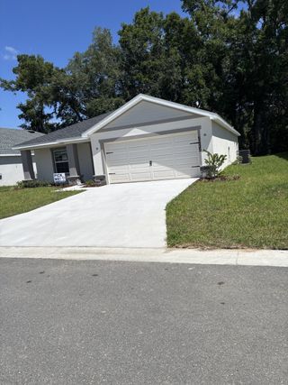 A charming white home with a lush yard in Bennah Oaks by Highland Homes of Florida, Belleview, FL.