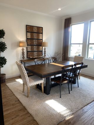 A cozy dining room with a wooden table, plush rug, elegant chairs, and decorative wall art.
